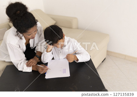 Teacher helping young boy with homework at home Teacher helping young boy with homework at home 127135839