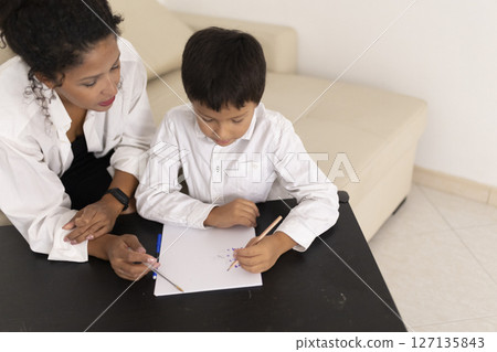Teacher helping child drawing with pencils at home Teacher helping child drawing with pencils at home 127135843