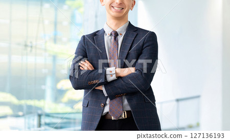 Smiling male businessman with arms crossed Smiling male businessman with arms crossed 127136193