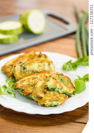 appetizing zucchini fritters with green onions in a plate on a wooden table appetizing zucchini fritters with green onions in a plate on a wooden table 127136351
