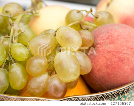 Still life of grapes and peaches in a plate. 127136567