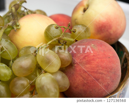 Still life of grapes and peaches in a plate. 127136568