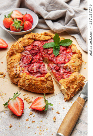Delicious homemade strawberry galette with almond petals baking on parchment paper Delicious homemade strawberry galette with almond petals baking on parchment paper 127137279