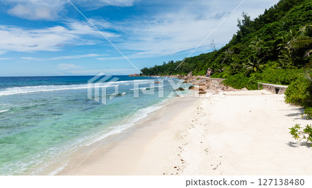 Shallow clear waters with patches of coral along a coastline bordered by a narrow white sandy beach. Seychelles, La Digue. Shallow clear waters with patches of coral along a coastline bordered by a narrow white sandy beach. Seychelles, La Digue. 127138480