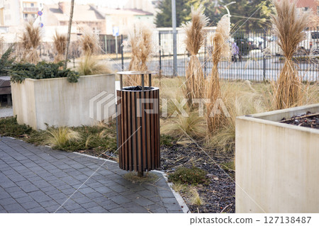 Wooden Public trash can on a city street filled with garbage. Garbage bin in park with blurred background 127138487