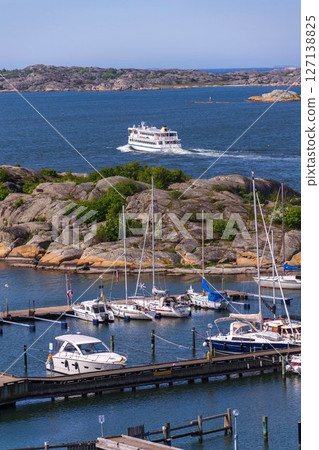 Archipelago ferry leaving harbour with ships at Saltholmen peninsula on the shore of Alvsborgsfjorden, Alvsborg district, Gothenburg, Sweden, sunny day 127138825