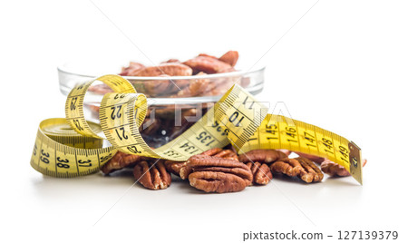 Peeled pecan nuts and measuring tape isolated on white background. Peeled pecan nuts and measuring tape isolated on white background. 127139379