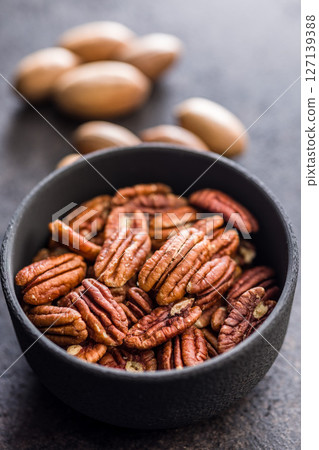 Peeled pecan nuts in bowl on black table. 127139388