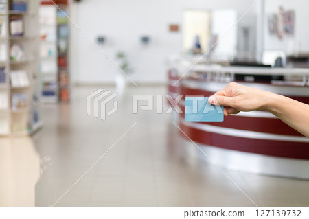 Hand holding a blue card in a modern reception area 127139732