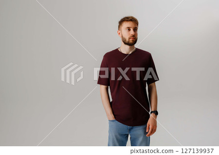Young man posing casually in a studio with a neutral background for a fashion shoot Young man posing casually in a studio with a neutral background for a fashion shoot 127139937