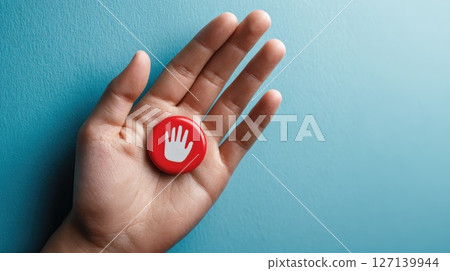 Hand Holding a Red Button Featuring a White Hand Symbol on Blue Background 127139944