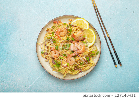 Pad thai noodles with shrimps and chopsticks on light blue background, traditional dish of Thailand Pad thai noodles with shrimps and chopsticks on light blue background, traditional dish of Thailand 127140431