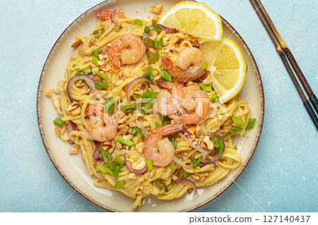 Pad thai noodles with shrimps and chopsticks on light blue background, traditional dish of Thailand Pad thai noodles with shrimps and chopsticks on light blue background, traditional dish of Thailand 127140437