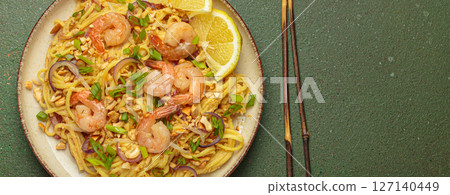 Pad thai noodles with shrimps and chopsticks on rustic green background, traditional dish of Thailand, space for text 127140449