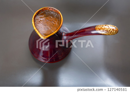 cezve with Turkish coffee on a gray surface. Ideal for modern cafe decor, coffee recipes, cezve with Turkish coffee on a gray surface. Ideal for modern cafe decor, coffee recipes, 127140581