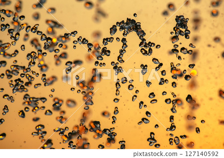 silhouettes of drops falling water fountain against the backdrop of the setting sun 127140592