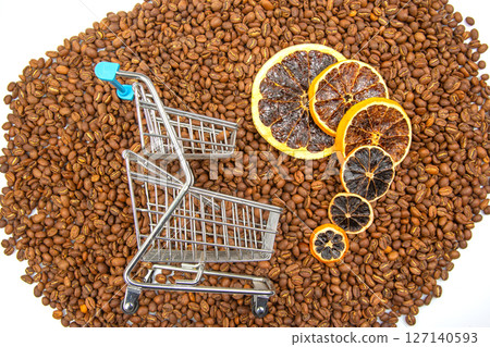 Artistic composition featuring a tiny cart on coffee beans with dried orange slices Artistic composition featuring a tiny cart on coffee beans with dried orange slices 127140593