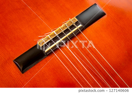 Detailed image of a vibrant red guitar bridge with freshly strung wires and a bundle Detailed image of a vibrant red guitar bridge with freshly strung wires and a bundle 127140606
