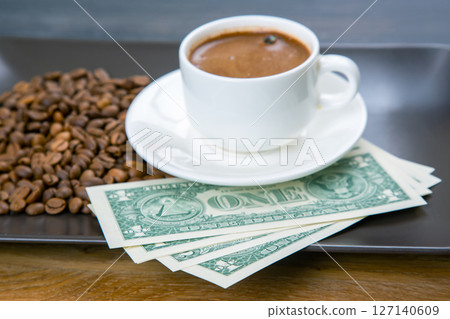 Coffee, money, and business. A cup of espresso with roasted coffee beans and U.S. currency 127140609