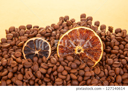 A vibrant close-up of dried orange slices nestled among roasted coffee beans 127140614