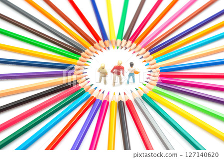 A creative composition featuring three small figures within a circle of assorted colored pencils A creative composition featuring three small figures within a circle of assorted colored pencils 127140620