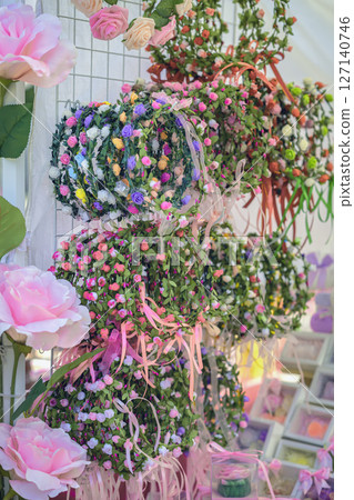 Colorful floral wreaths for hair, handmade decor hanging on market stand in daylight. Traditional festive decoration during annual rose festival in Bulgaria 127140746