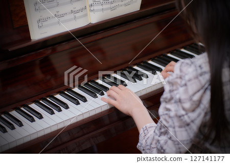 A young lady playing the piano 127141177