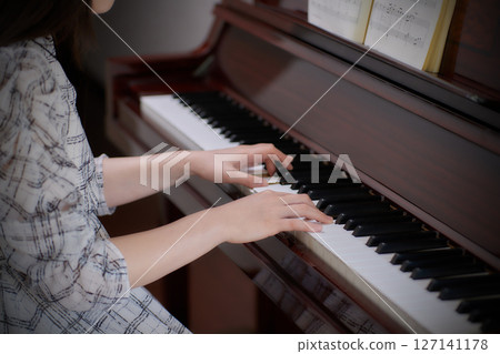 A young lady playing the piano 127141178