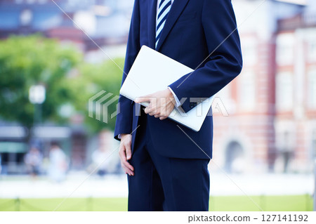 Young businessman with laptop in business district Young businessman with laptop in business district 127141192
