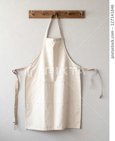 Off-White Cotton Apron Hanging on Wooden Hook 127141846