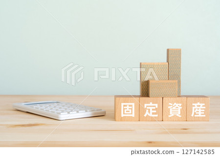Blocks with the words "Fixed assets" written on them, a model of a real estate property, and a calculator Blocks with the words "Fixed assets" written on them, a model of a real estate property, and a calculator 127142585
