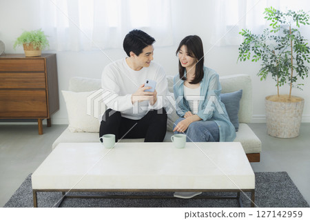 看一台智能手機的年輕夫婦在客廳 127142959