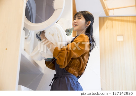 A woman taking laundry out of a drum washing machine 127142980