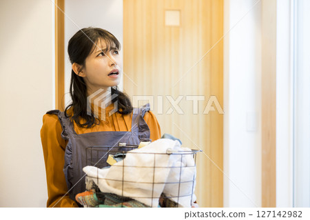 A woman taking laundry out of a drum washing machine 127142982