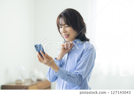 A woman using a smartphone in the living room 127143043