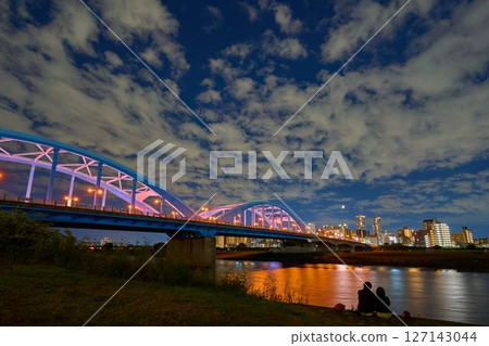 People looking at the view of Maruko Bridge across Nakahara Ward, Kawasaki City, and the high-rise apartment buildings on a moonlit night 127143044