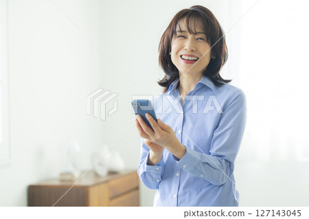 A woman using a smartphone in the living room 127143045