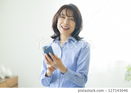 A woman using a smartphone in the living room 127143046