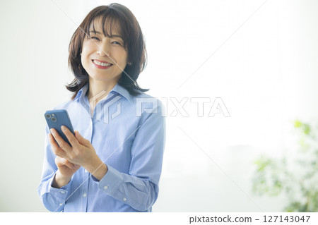 A woman using a smartphone in the living room 127143047