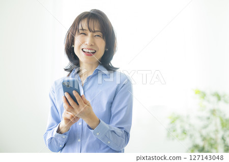 A woman using a smartphone in the living room 127143048