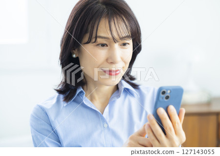 使用智能手機的婦女在客廳 使用智能手機的婦女在客廳 127143055