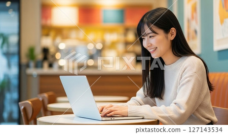 Work-life balance in the era of hybrid work: A woman opening her laptop in a cafe 127143534