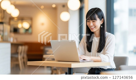 Work-life balance in the era of hybrid work: A woman opening a laptop in a cafe Work-life balance in the era of hybrid work: A woman opening a laptop in a cafe 127143656