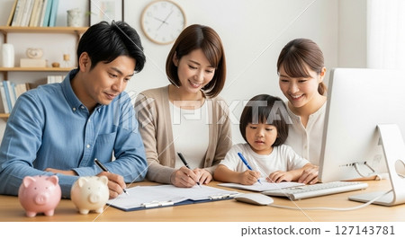 為家庭的未來投資:一家人圍坐在一本家庭帳簿和一台電腦旁 為家庭的未來投資:一家人圍坐在一本家庭帳簿和一台電腦旁 127143781