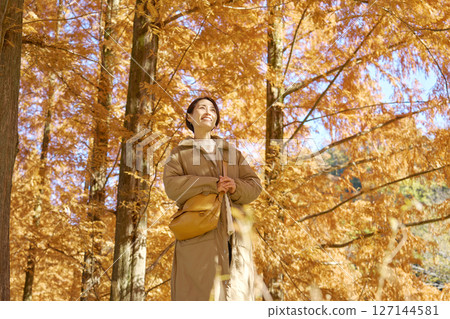 Middle-aged woman walking among autumn leaves Middle-aged woman walking among autumn leaves 127144581