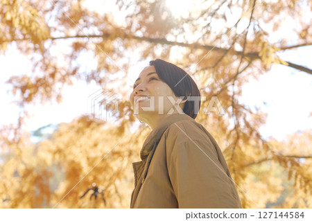 Middle-aged woman walking among autumn leaves 127144584