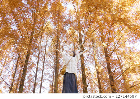 一名中年婦女在秋葉中深吸一口氣，全身 127144597