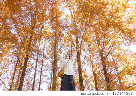 一名中年婦女在秋葉中深吸一口氣，全身 127144598