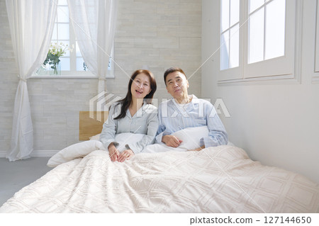 A couple waking up in bed, portrait, looking at camera A couple waking up in bed, portrait, looking at camera 127144650