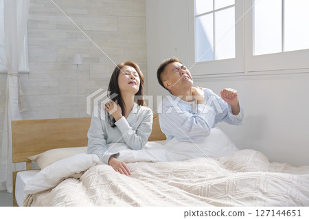 A couple waking up in bed, tired A couple waking up in bed, tired 127144651